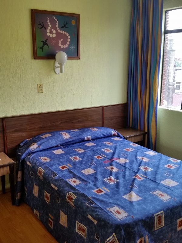 Interior of hotel room, bed and window.