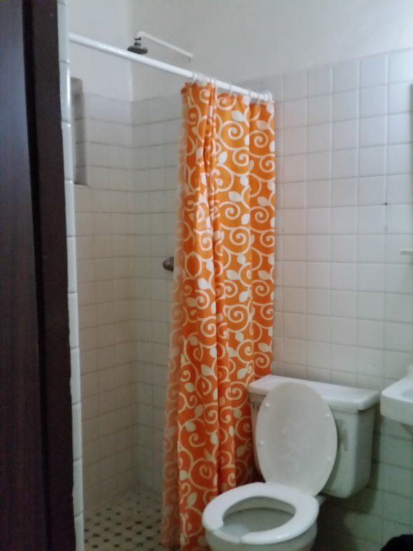 Orange shower curtain in a hotel bathroom.