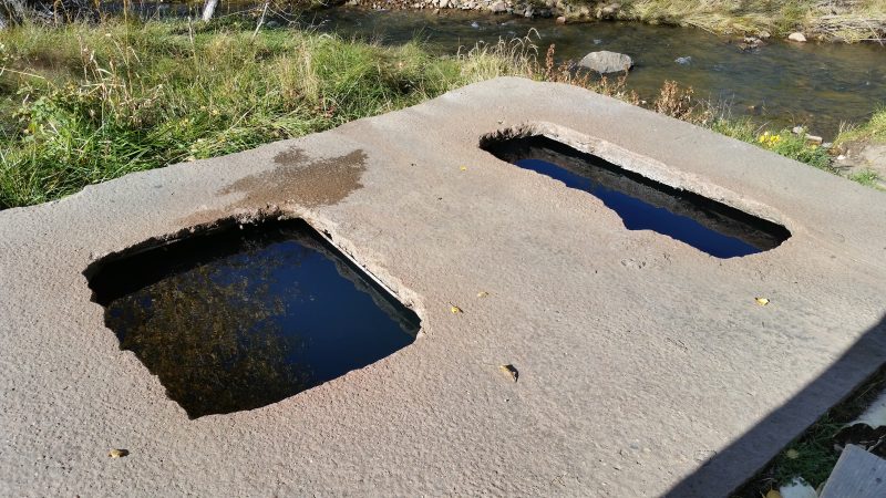 A concrete slap with two holes cut into it, filled with hot spring water at Montezuma Hot Springs near Las Vegas, New Mexico.