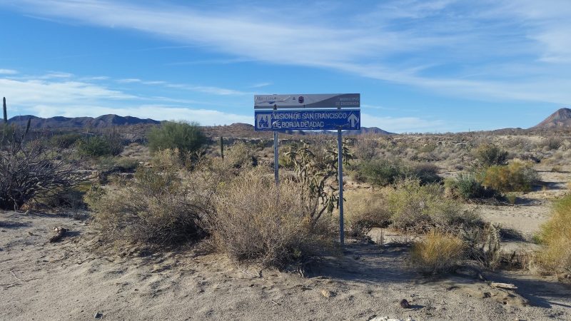 A sign in the middle of the baja desert pointing to two roads.