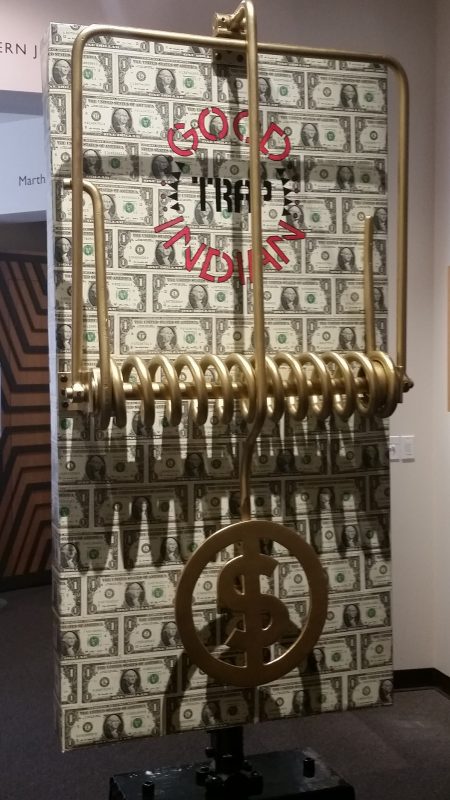 An art installation from Bob Haozous of a large mousetrap lined with US $1 bills.
