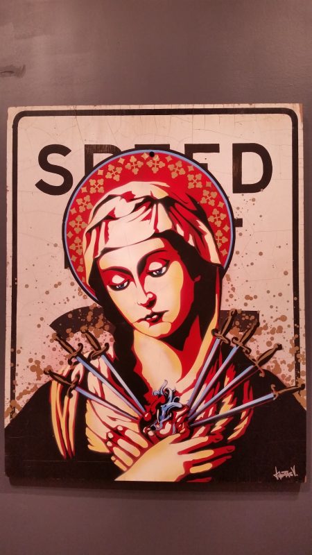 An old speed limit sign with a Virgin Mary image on it.