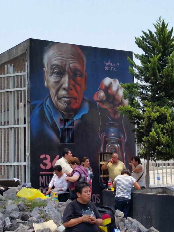 The side of a building in Mexico City painted with the image of an old man holding a lantern.