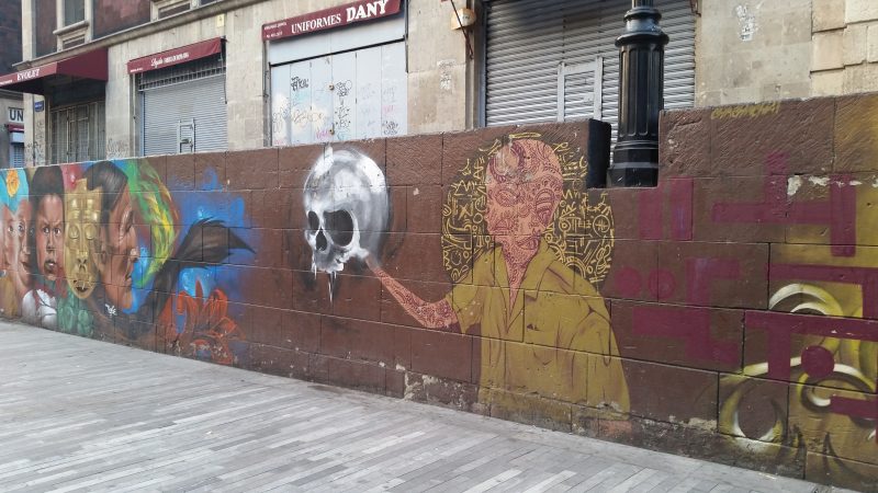 A street art painting in Mexico City depicting a man in a yellow shirt holding a skull.
