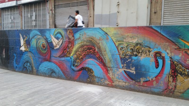 A man walking above a colorful Mexico City street art mural.