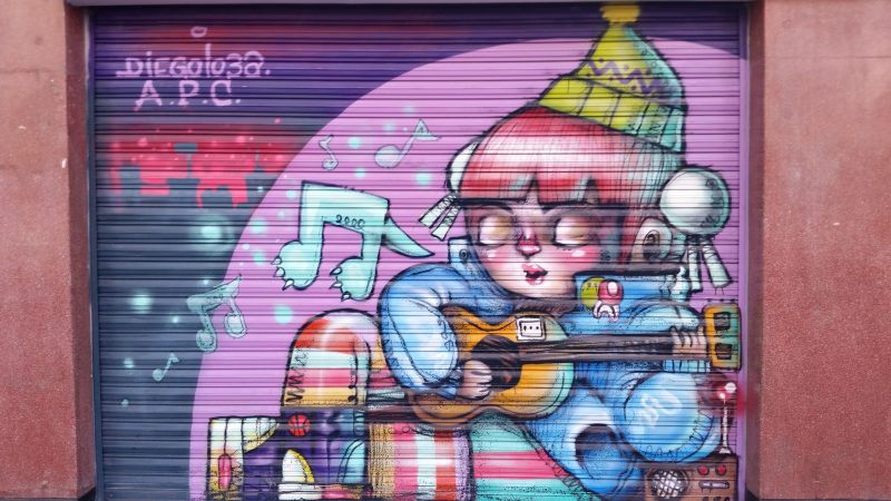 Street art in Mexico City showing a cartoonish image of a young girl playing a guitar and singing.
