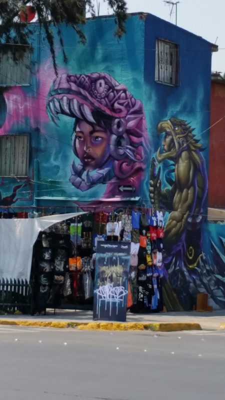 A building in Mexico City with a fantasy-style mural painted on its side.