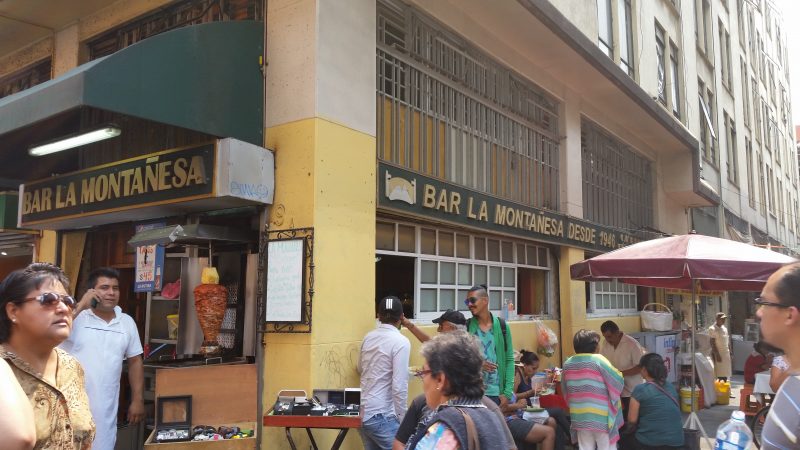 People in Mexico City walking outside the Bar La Montanesa cantina.