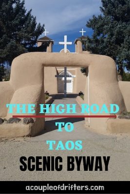 An adobe church with pine trees on either side against a blue sky.