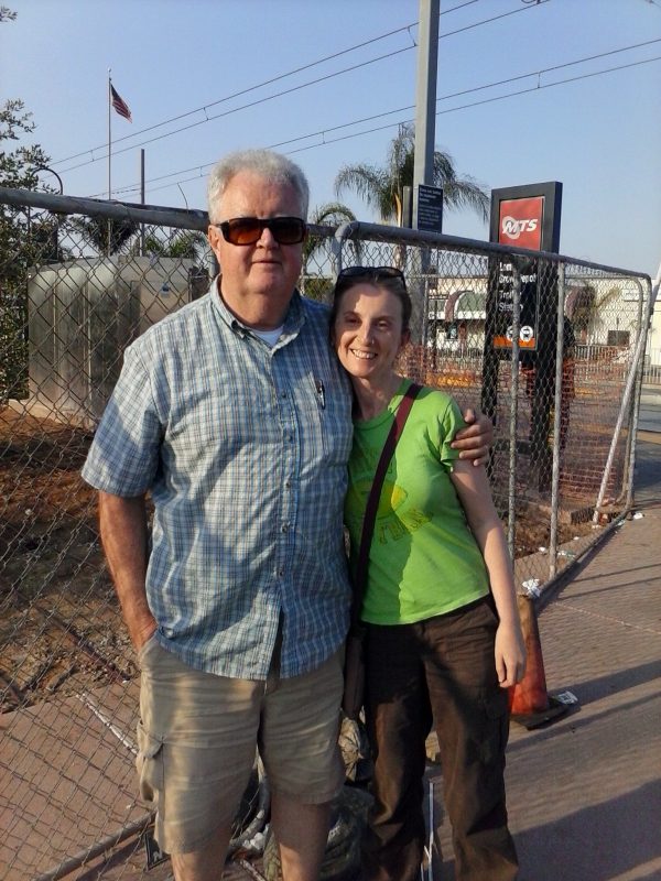 Man and woman in front of a chain link fence.