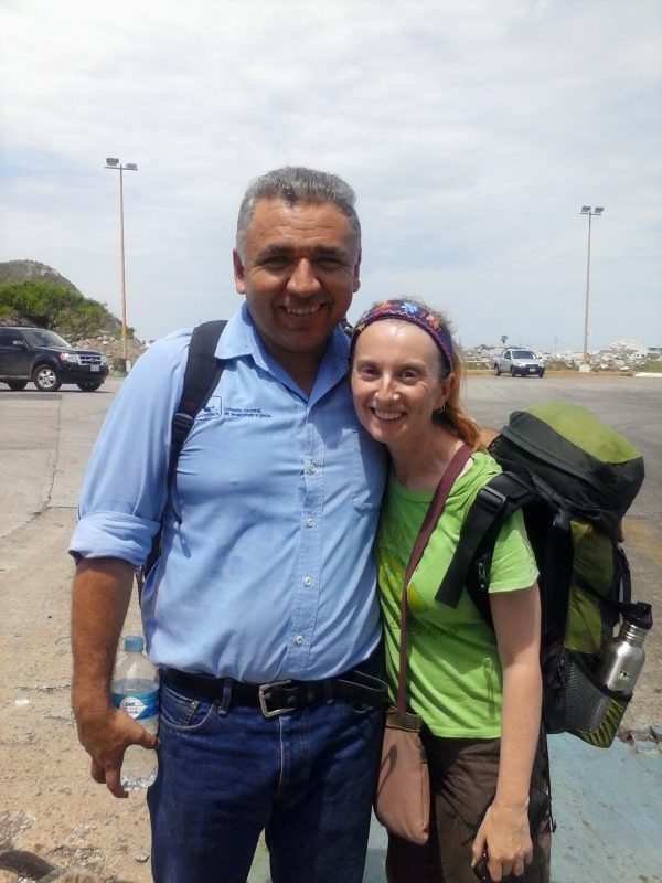 Man with blue shirt and woman with green shirt and backpack posing with smiles.