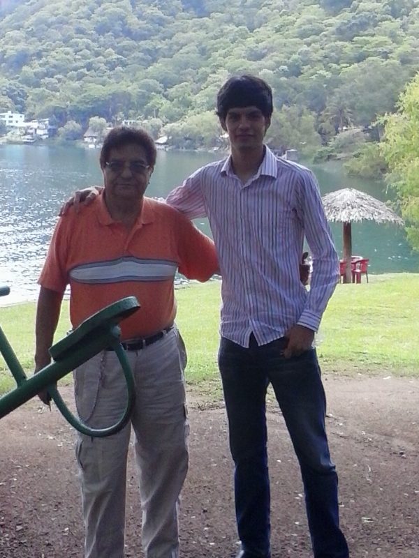 Two men posing arm in arm in front of a lake.