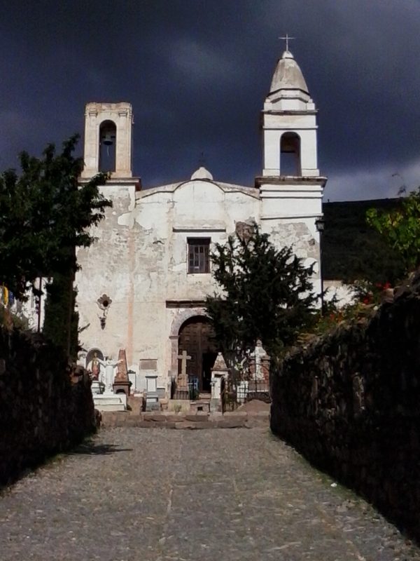 A white church agains the background of a very dark sky in the town of Real de Catorce in the state of San Luis Potosi in Mexico