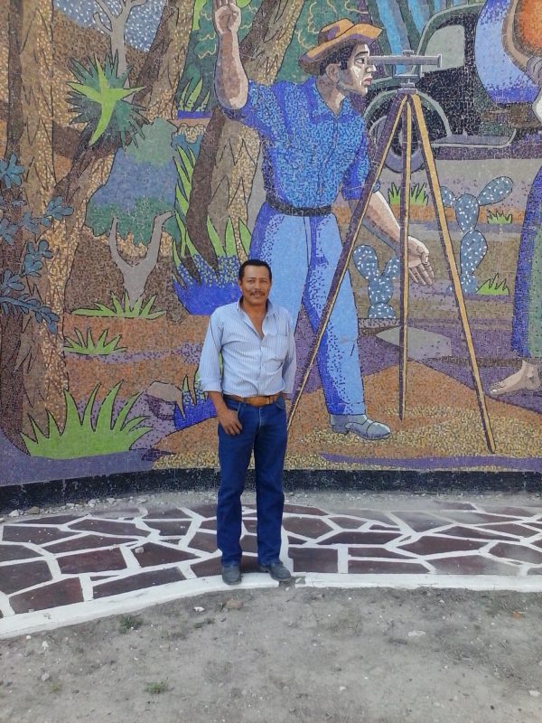 Man posing in front of a colorful mosaic.