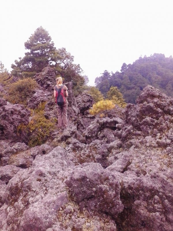 A woman with a backpack standing in a lava field.