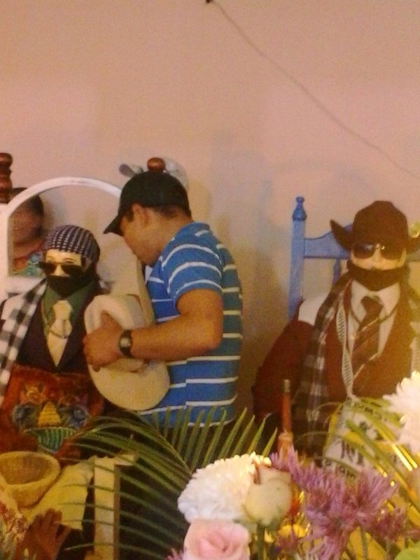 A man and woman pouring spirits into the mouth of San Simon in Zunil, Guatemala.