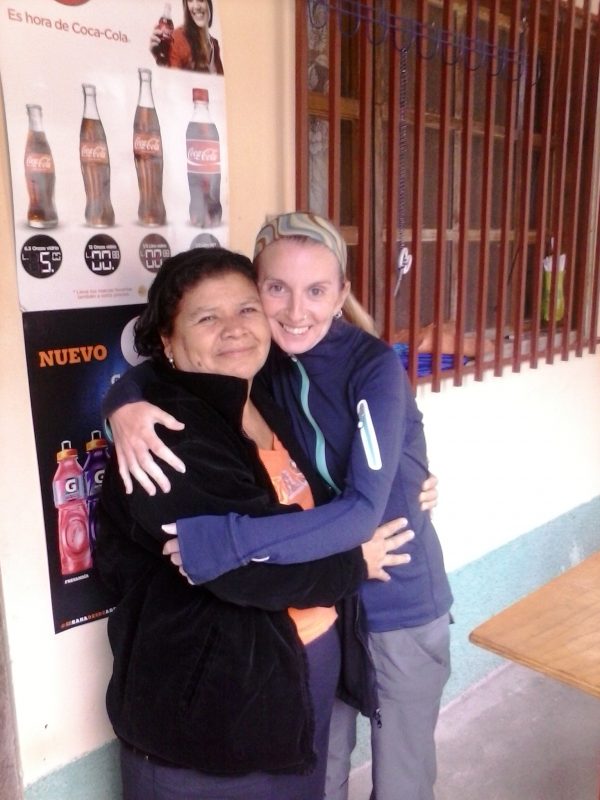 Two women hugging in front of a shop in Honduras.