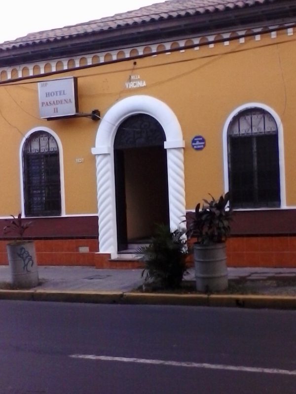 The front exterior entrance of the yellow-colored Hotel Pasadena II in San Salvador, El Salvador.
