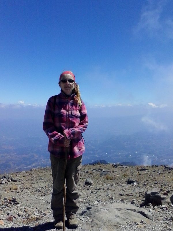 A woman wearing a pink flannel smiling after hiking Volcan Tajumulco.