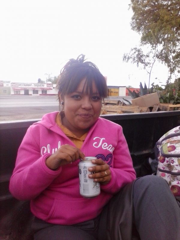 Woman in a pink pull-over drinking a can of beer.