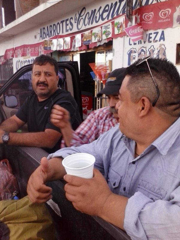 Three men leaning against a pick up truck.