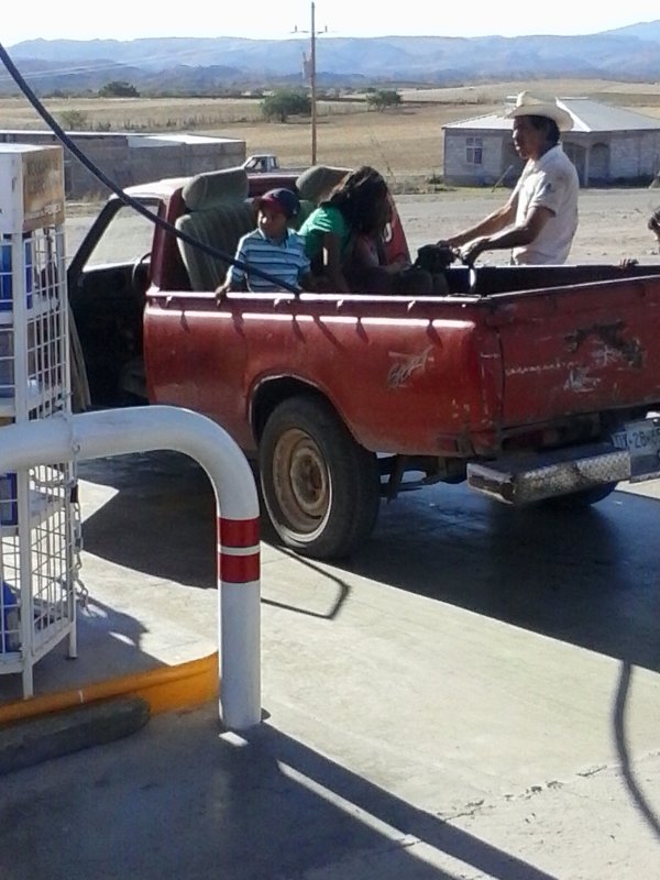 people in the back of a pick-up truck at a gas station.