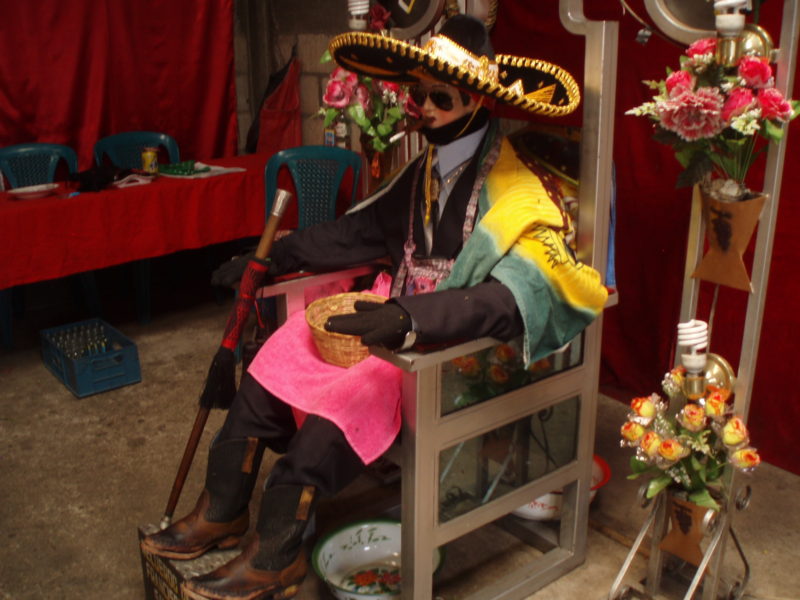 The likeness of San Simon in Zunil, Guatemala, wearing a sombrero and sunglasses, as is typical.